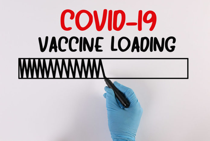 Doctor writing Covid-19 Vaccine Loading Corona