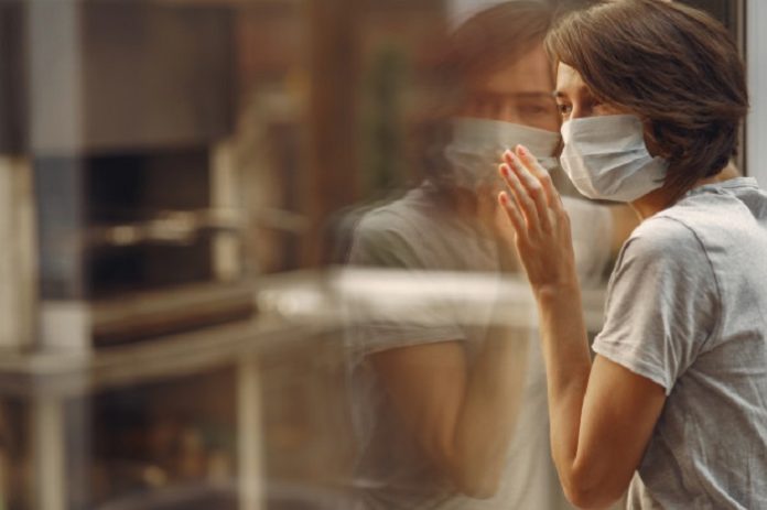 woman-mask-stands-by-window_1157-31619 lockdown Corona