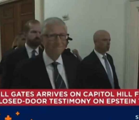 Bill Gates betrapt op een grijns terwijl hij een besloten Epstein-hoorzitting binnengaat, afgeschermd van het publiek